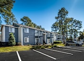 Thumbnail 6 of 35 - A row of townhouses with a car parked in front.