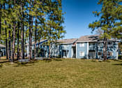 Thumbnail 9 of 35 - A large grassy area in front of a building with trees on the left.
