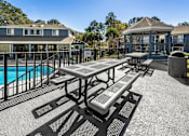Thumbnail 31 of 35 - A picnic table and benches are set up on a patio next to a pool.