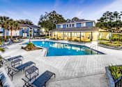 Thumbnail 32 of 35 - A swimming pool surrounded by a concrete patio and lounge chairs.