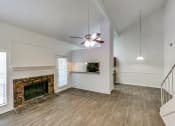 Thumbnail 16 of 25 - an empty living room with a fireplace and a ceiling fan