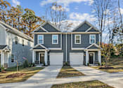 Thumbnail 19 of 22 - A two-story house with a garage is surrounded by trees and other houses.