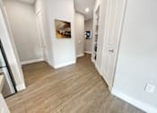 Thumbnail 19 of 30 - a living room and hallway with wood flooring and white walls