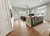 Thumbnail 16 of 30 - A modern kitchen with a wooden floor and white walls.