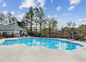 Thumbnail 25 of 45 - A large swimming pool with a house and trees in the background.