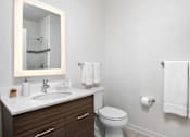 Thumbnail 15 of 25 - A white toilet sits next to a sink in a bathroom.