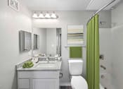 Thumbnail 14 of 14 - A bathroom with a green shower curtain and a white toilet.