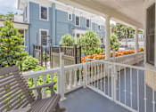 Thumbnail 19 of 23 - A wooden bench sits on a porch with a white railing.