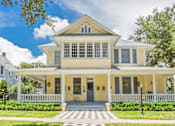 Thumbnail 20 of 23 - A yellow house with a white porch and a grey door.