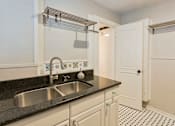 Thumbnail 8 of 23 - A kitchen with a sink and a black counter top.