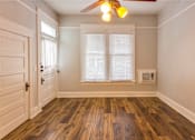 Thumbnail 6 of 23 - A room with a ceiling fan and wooden flooring.
