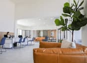 Thumbnail 17 of 66 - a large room with leather chairs and tables and a woman sitting at a desk