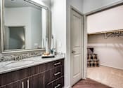 Thumbnail 8 of 22 - A bathroom with a mirror, sink, and wooden cabinets.