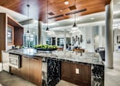 Thumbnail 14 of 22 - A modern kitchen with a marble countertop and wooden accents.