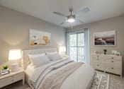 Thumbnail 7 of 31 - A bedroom with a large bed, a ceiling fan, and a view of the outdoors through a sliding glass door.