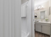 Thumbnail 6 of 31 - A white bathroom with a sink, mirror, and a towel hanging on the wall.