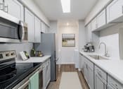 Thumbnail 4 of 31 - A modern kitchen with white cabinets and a stainless steel oven.