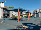 Thumbnail 35 of 66 - an outdoor playground with a picnic table and swing set in front of apartments