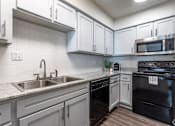 Thumbnail 41 of 66 - an empty kitchen with white cabinets and black appliances