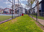 Thumbnail 50 of 66 - a fenced in grassy area with a playground next to a chain link fence