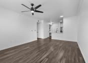 Thumbnail 19 of 25 - a bedroom with a ceiling fan and a kitchen in the background