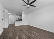 Thumbnail 7 of 25 - a bedroom with a ceiling fan and a kitchen in the background