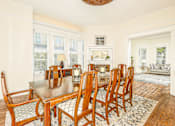 Thumbnail 12 of 23 - A dining room with a wooden table and chairs.