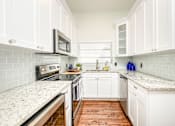Thumbnail 10 of 23 - A kitchen with white cabinets and a granite countertop.