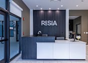 Thumbnail 7 of 34 - A reception area with a white counter and a sign that says "RESIA".