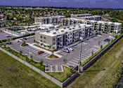 Thumbnail 11 of 34 - A large apartment complex with a parking lot in front.