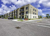 Thumbnail 8 of 34 - A large building with a parking lot in front of it.