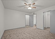 Thumbnail 63 of 66 - an empty living room with a ceiling fan and a door to a bathroom