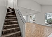 Thumbnail 61 of 66 - the living room and staircase of an apartment with a hardwood floor and a window