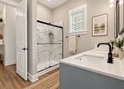 Thumbnail 10 of 33 - A bathroom with a white sink and a glass shower door.