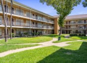 Thumbnail 27 of 29 - a grassy area with trees and a walkway in front of an apartment building