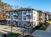 Thumbnail 5 of 11 - Apartment complex with a black fence in front.