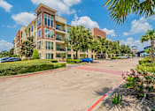 Thumbnail 4 of 35 - A multi-story apartment building with a parking lot in front.