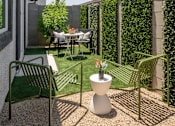 Thumbnail 11 of 21 - A patio with a table, chairs, and a planter.