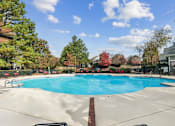 Thumbnail 22 of 45 - A large swimming pool surrounded by trees and a fence.
