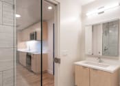 Thumbnail 14 of 15 - A modern bathroom with a walk-in shower and a double sink vanity.