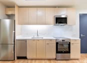 Thumbnail 7 of 15 - A kitchen with a refrigerator, microwave, and oven.