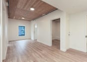 Thumbnail 10 of 15 - A room with wooden floors and white walls.