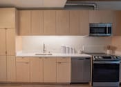 Thumbnail 11 of 15 - A kitchen with wooden cabinets and a stainless steel oven.