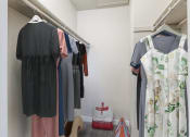 Thumbnail 10 of 20 - a walk in closet with clothes hanging on a rack and a closet organizer with a