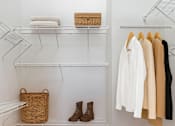 Thumbnail 3 of 20 - A white closet with clothes hanging and a basket on the shelf.