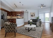 Thumbnail 1 of 20 - A modern living room with a grey sofa and a patterned armchair.