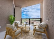 Thumbnail 5 of 20 - A balcony with two chairs and a table with a view of the sky and buildings.