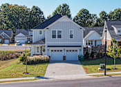 Thumbnail 32 of 33 - A white house with a grey roof is surrounded by other houses.