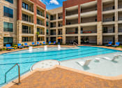 Thumbnail 6 of 35 - A large swimming pool in front of a multi-story apartment building.