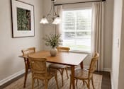 Thumbnail 27 of 37 - A dining room with a wooden table and chairs.